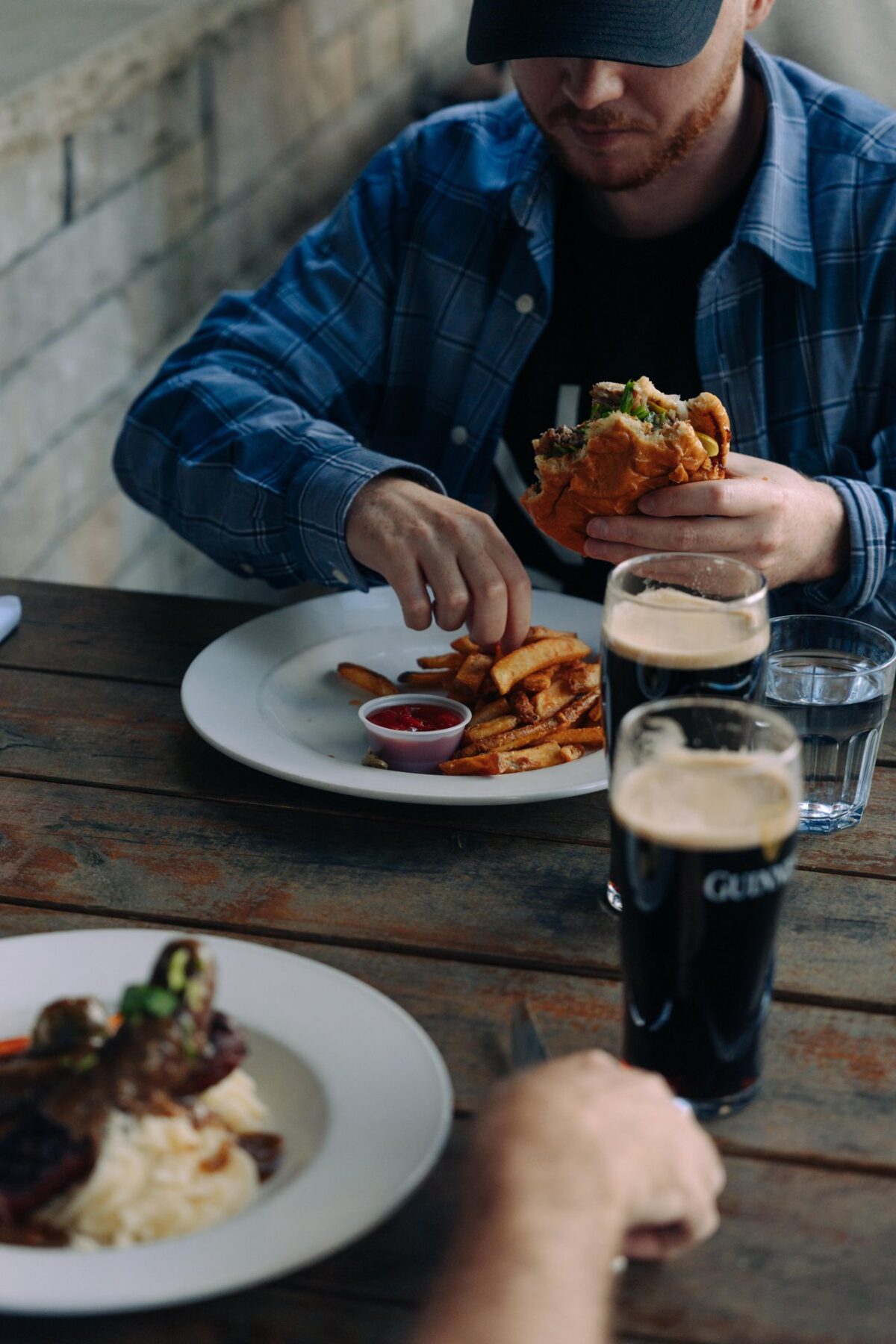 A man eating a burger and fries with a Guinness at The Brown Hound Ironstone Ln.