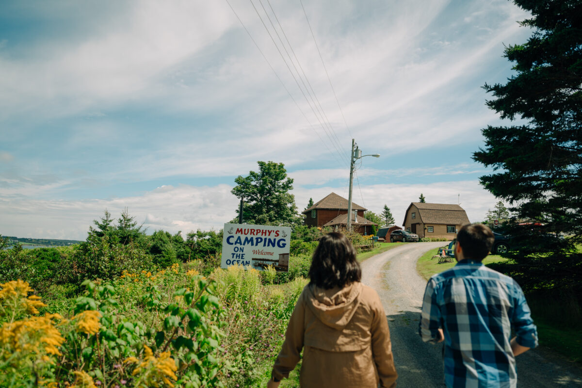 Visitors walking toward Murphy’s Camping on the Ocean on Nova Scotia’s Eastern Shore, with coastal views and cottages ahead