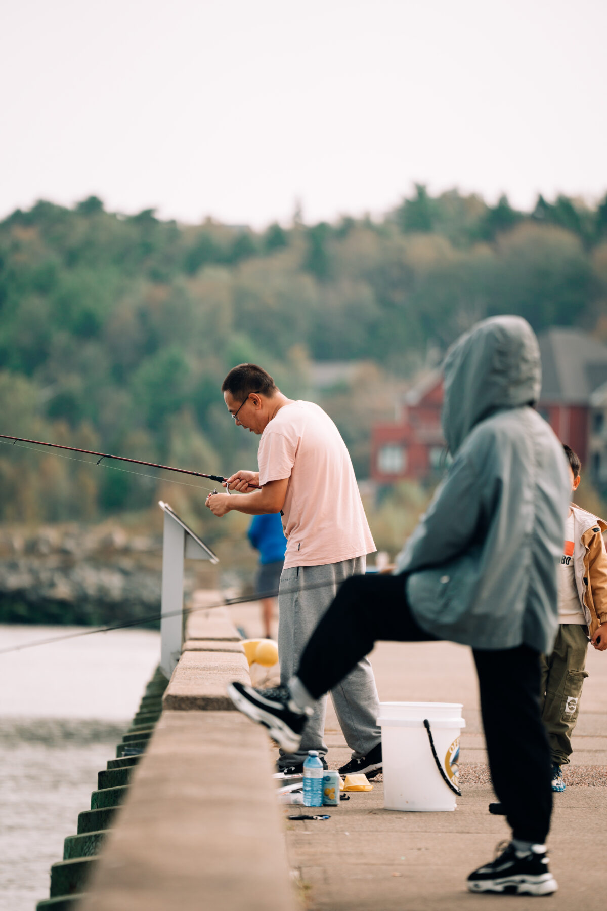People fishing from the waterfront at DeWolf Park in Bedford, Nova Scotia, casting lines into the harbour on a calm day