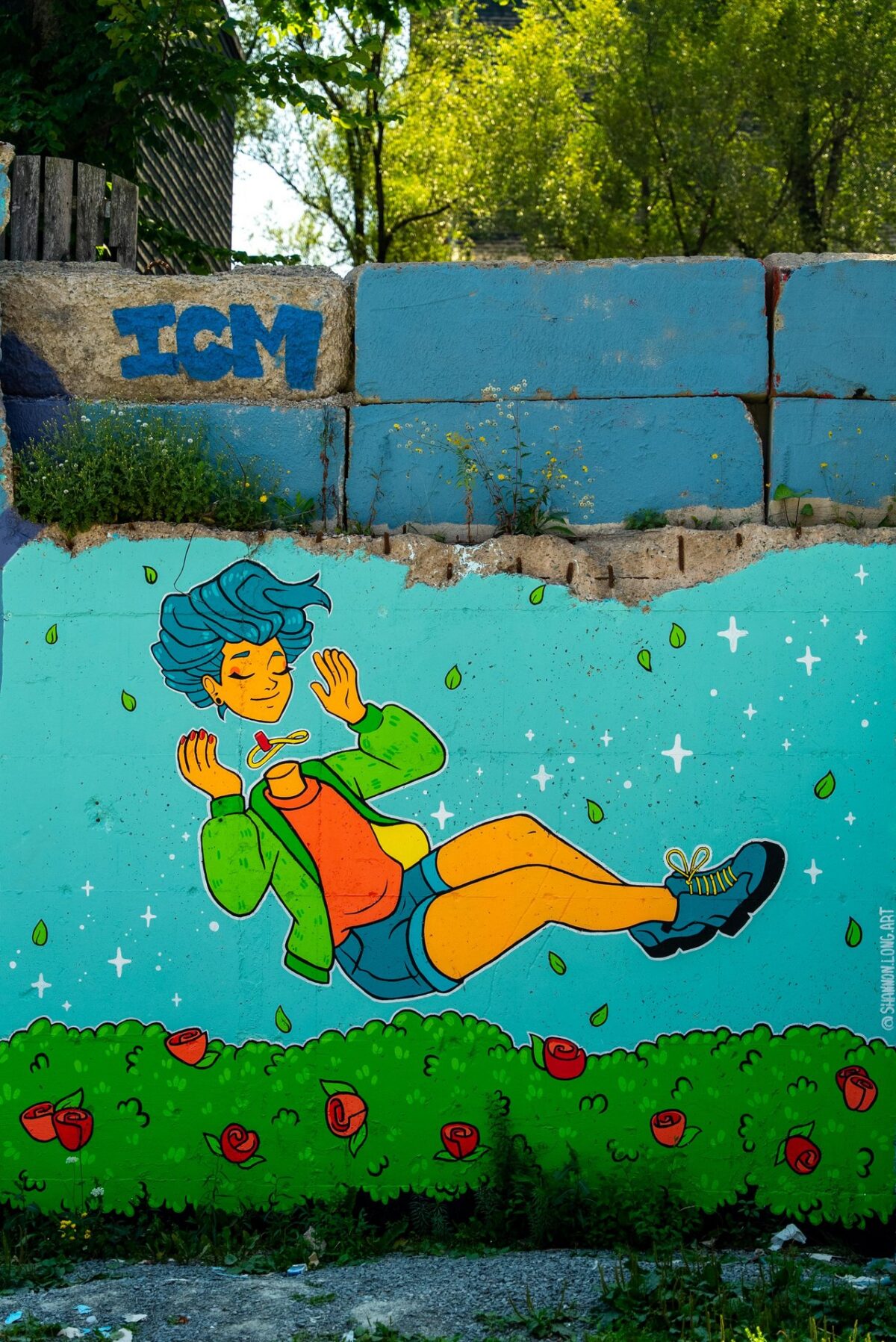 A bright, cartoon-style mural of a person with blue hair floating on their back among green bushes and red flowers, set against a turquoise background.