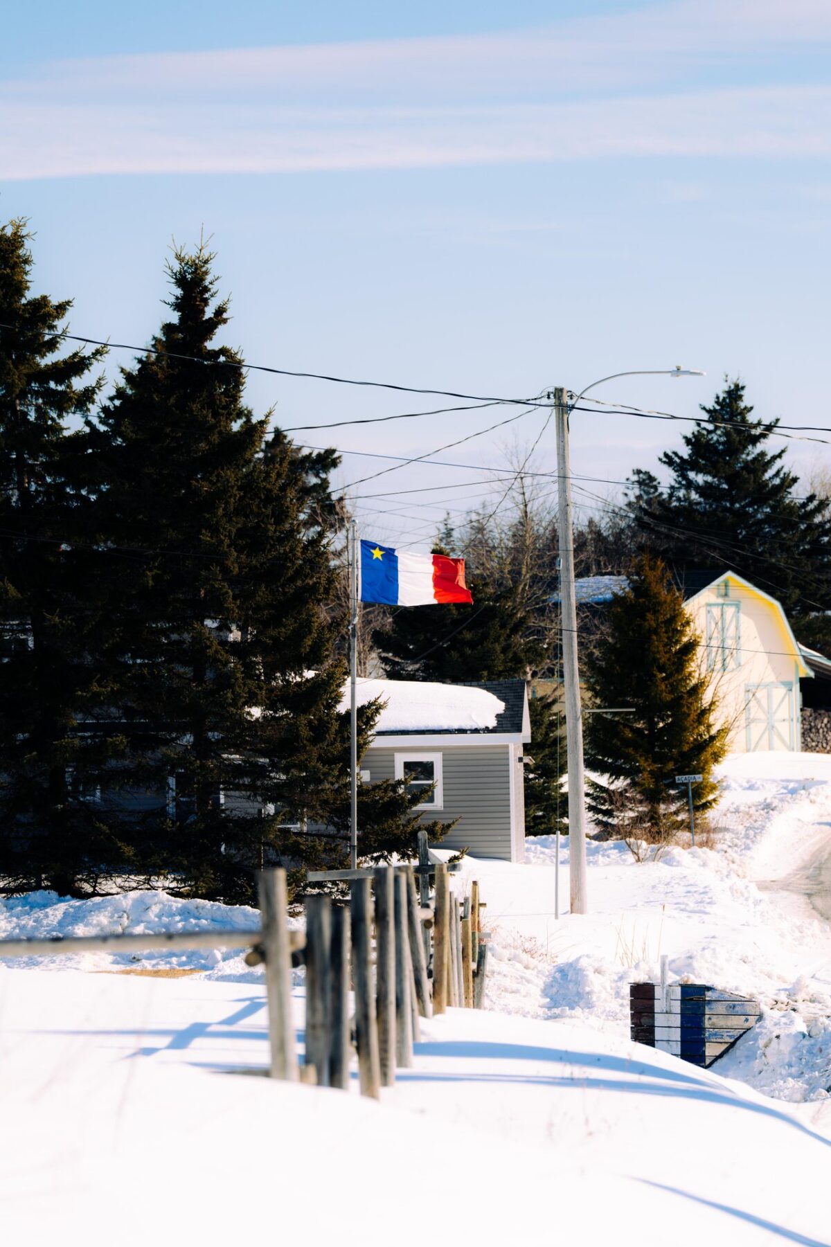 Acadian flag flying over the snowy grounds of L’Acadie de Chezzetcook.