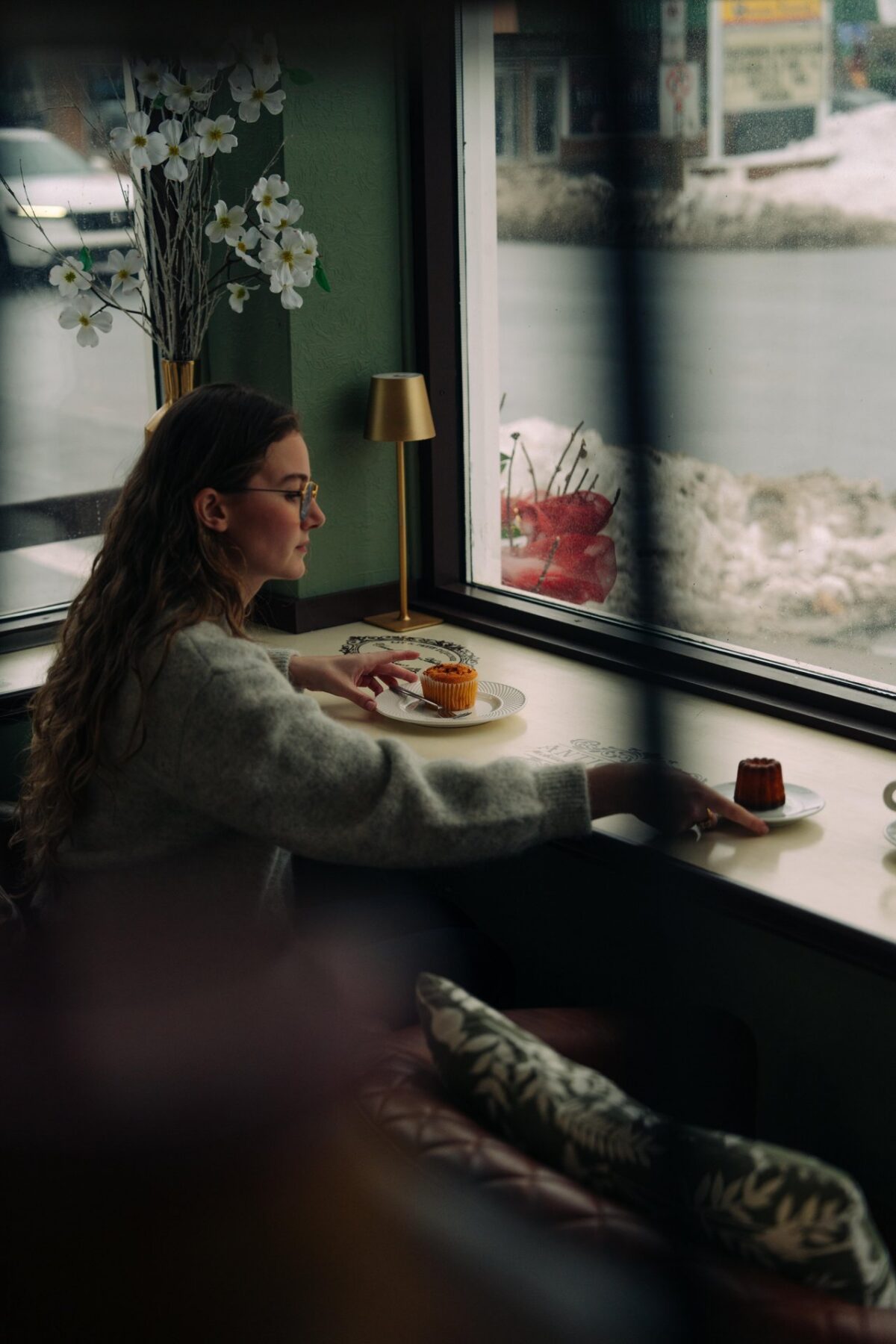 Person at Angélique Café sitting by the window with pastries.