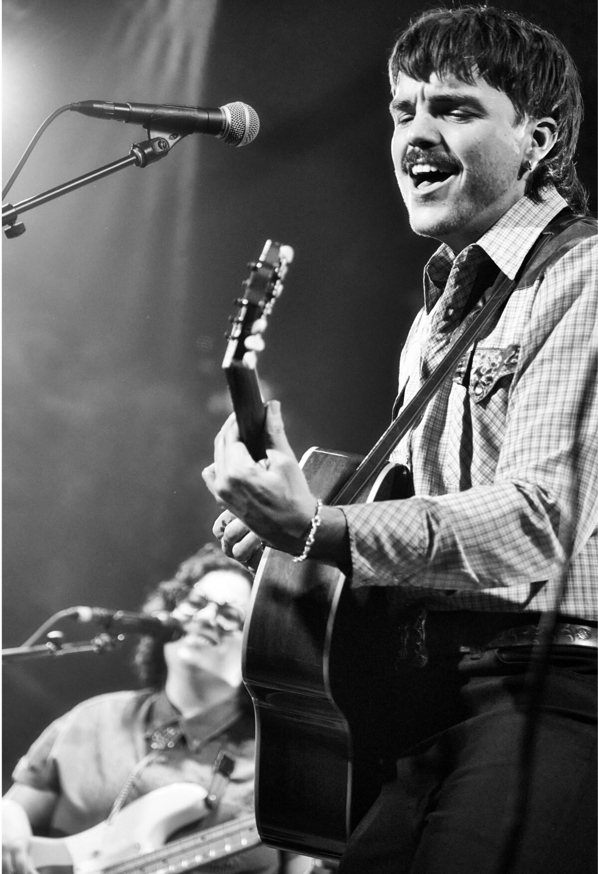 Halifax indie musician Braden Lam performing live on stage with an acoustic guitar.