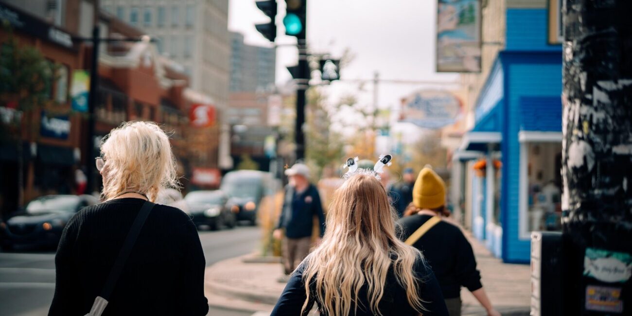 People walking along a street in Downtown Halifax with shops, pedestrians, and city buildings in the background.