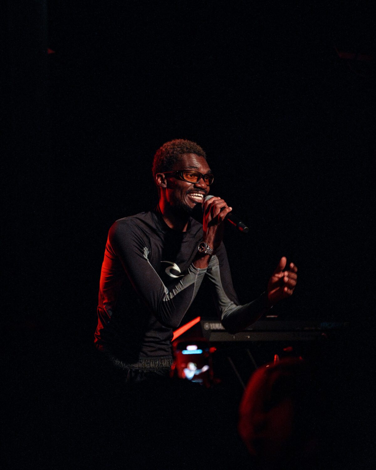Halifax afrobeats artist aRENYE performing live on stage with a microphone.