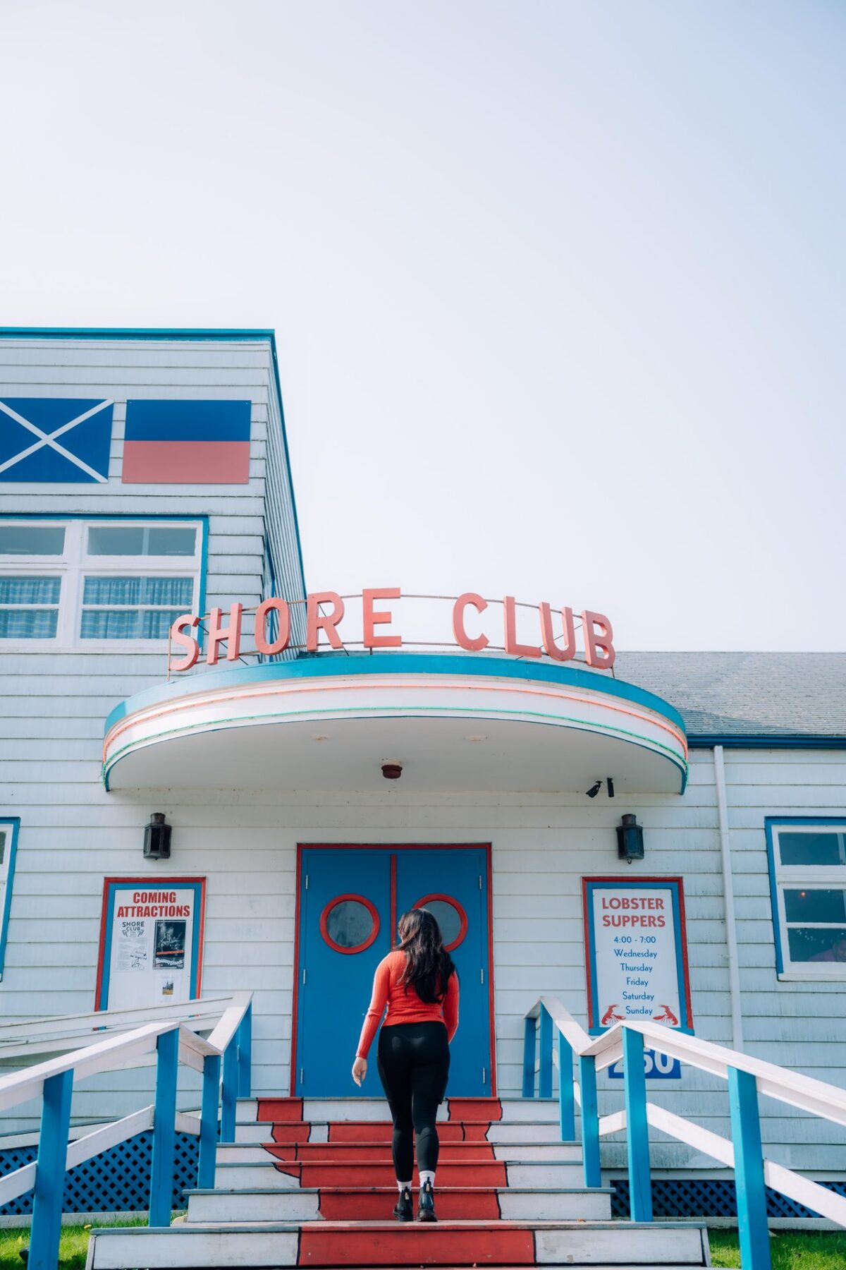 Person walking up the steps of the Shore Club to the front door